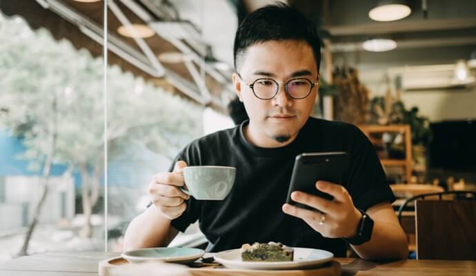Homme profitant d'un repas en regardant le téléphone portable qui lance Norton 360 Standard.